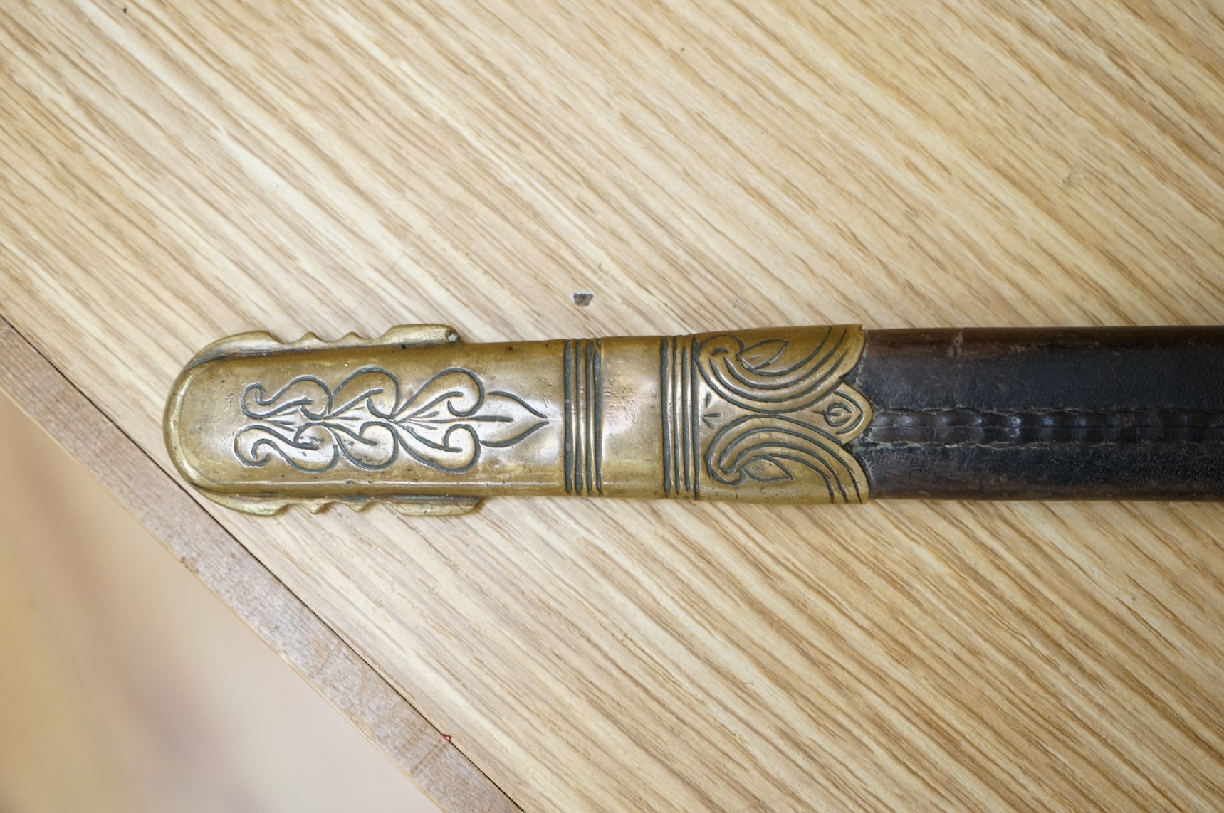 A post 1902 Naval Officer’s Dirk, the regulation blade with crowned fouled anchor, regulation hilt with remains of bullion dress knot in its leather scabbard with brass mounts, locket engraved with owners initials; RSA